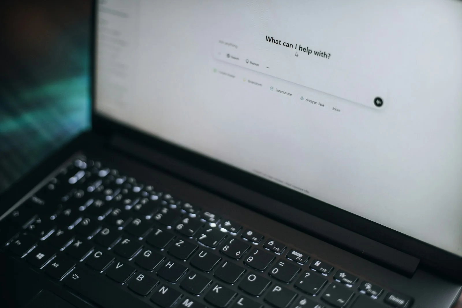 A laptop screen showing an AI chat assistant's 'What can I help with?' prompt