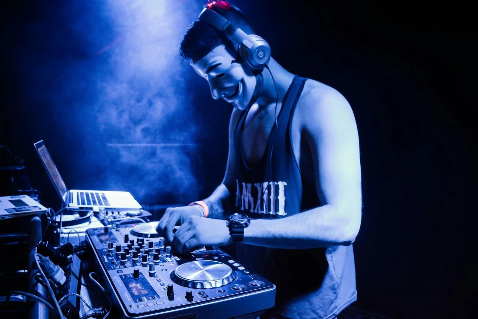 A DJ wearing headphones mixing on a controller at a party