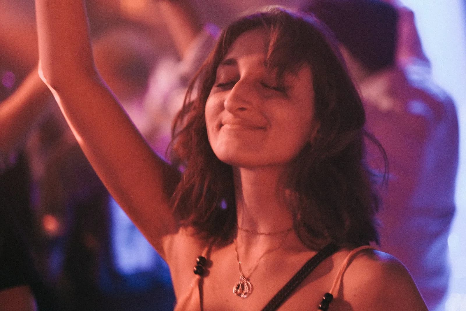 A woman smiling with her hand raised on a lit-up dance floor